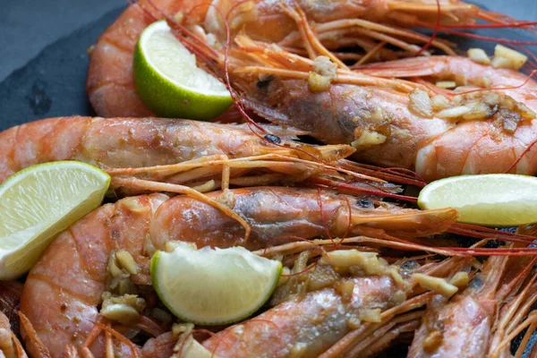 Siyah tabakta limonlu ve sarımsaklı kızarmış gambonlar.