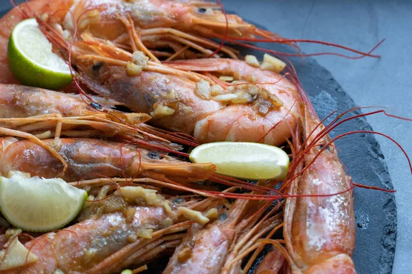 Siyah tabakta limonlu ve sarımsaklı kızarmış gambonlar.