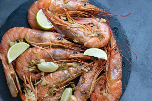 Siyah tabakta limonlu ve sarımsaklı kızarmış gambonlar.