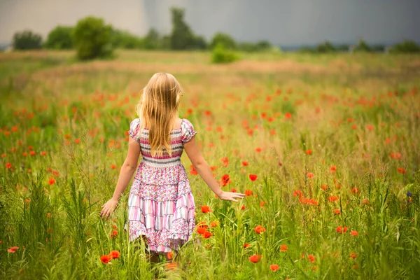 雨の前にカラフルなドレスでポピー畑の牧草地を歩いて顔のないブロンドの女の子 幸せな夏のコンセプト 自然に近い アレルギーの時間だ ブロンドの髪と赤いケシ — ストック写真