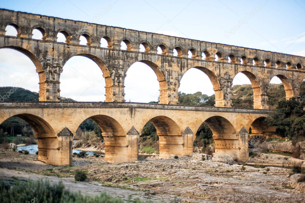 Roman aqueduct Pont du Gard above Gardon river, Unesco World Heritage site. Located near Nimes, Languedoc, France, Europe. Big stone roman arch. Travel tourism destination in Provence