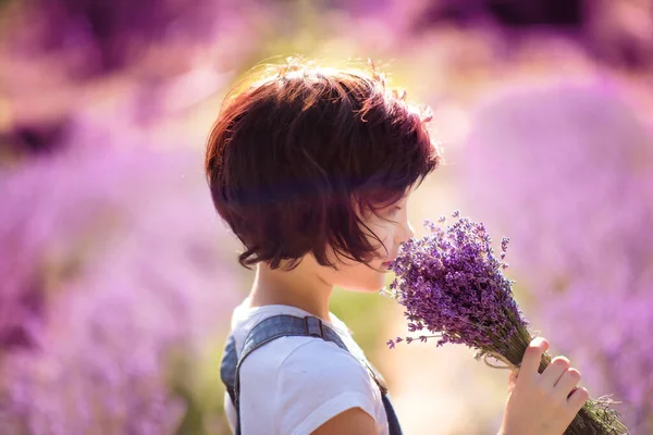 夏の晴れた日に周りの紫色の花とラベンダー畑でラベンダーの花束を嗅ぐボブヘアカットと幸せなかわいい女の子の花束の肖像画 プロヴァンスの夏 旅行だ ラベンダーの子 — ストック写真