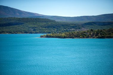 Fransa 'nın güneyindeki Sainte Croix Gölü' nün panoramik manzarası. 1973 yılından yapay göl. Göldeki panorama, küçük Provence kasabası manzaralı. Mükemmel sessiz su ve mavi gökyüzü. Alplerden dağcılar.