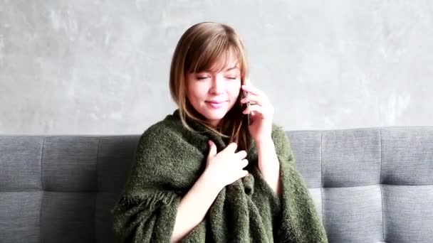 소파에 앉아 안락 한 실내에서 휴대폰으로 이야기하는 행복 한 젊은 여성. 집에 있는 동안 통화하는 백인예쁜 여자의 사진을 클로즈업하 세요. 레저 개념 — 비디오