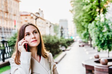 Şehir caddesinde telefonla konuşan dalgın, genç bir kadın. Küçük iş kadını cep telefonuyla konuşuyor. İş kadını telefon et. Telefonla iletişim