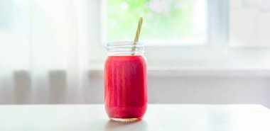 Beyaz mutfak masasında taze kırmızı meyve püresi. Yaz yemeği ve içecekleri. Konsept afişi. Ahududu, çilekli smoothie.