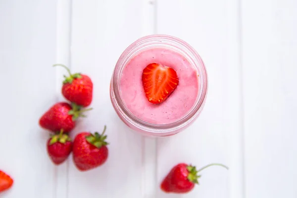 Ett glas färsk jordgubbssmoothie på en vit träbakgrund. Sommardryck shake, vegetarisk kost och förfriskning ekologiskt koncept. — Stockfoto