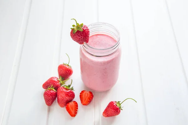 Smoothie de morango fresco em um fundo de madeira branco . — Fotografia de Stock