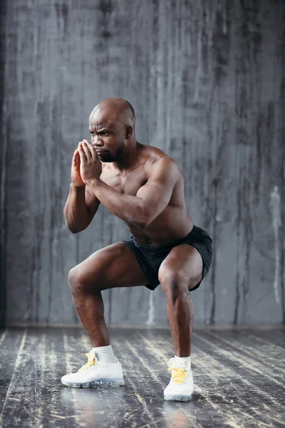 Um atleta afro-americano com músculos em relevo está treinando quadríceps e músculos das costas no estúdio . — Fotografia de Stock