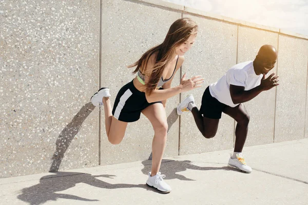 Atleta rubio y de piel oscura compiten en correr, empujando contra la pared. Deportes al aire libre — Foto de Stock