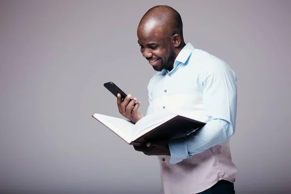 Πορτρέτο ενός μελαμψού άνδρα επιχειρηματία με πουκάμισο που κρατάει ένα τηλέφωνο στα χέρια του και ένα φάκελο με έγγραφα στο στούντιο — Φωτογραφία Αρχείου