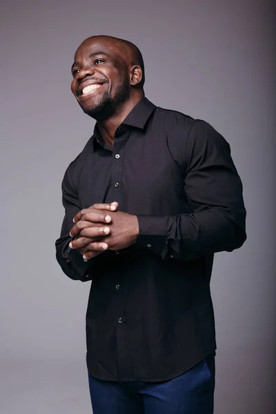 Hombre afroamericano con una camisa negra de pie con los brazos cruzados y sonriendo. La gente se alegra por el éxito en el trabajo . — Foto de Stock