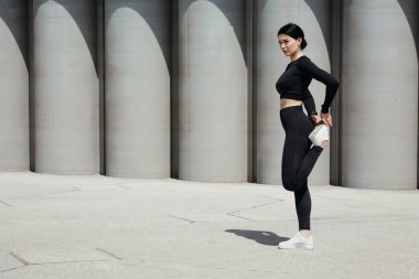 Spor elbiseli bir kız bacaklarıyla ısınıyor ve onları sokağa fırlatıyor..