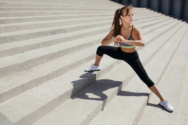 フィットネストレーナーは、運動をストレッチし、公園内の階段で内側太ももの筋肉を開発 — ストック写真