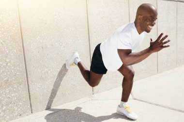 Profesyonel bir siyah koşucu uzun mesafe koşusuna başlamak için duvardan tekmeliyor.