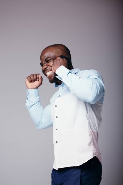Beyaz gömlekli bir zencinin portresi telefonla konuşuyor ve başarının bir işareti olarak elini yumruk ile tutuyor.