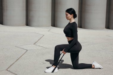 Bacağına lastik ihracatçısı takıp parkta diz çöküp kol kaslarını çalıştıran Asyalı bir antrenörün profili.