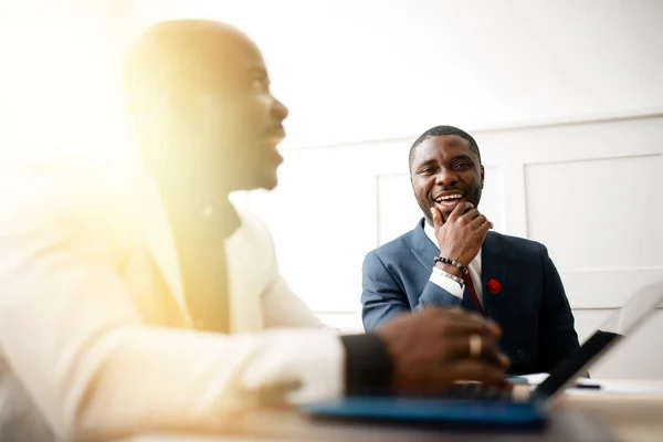 Dwóch czarnych afrykańskich biznesmenów w garniturach rozmawia i organizuje konferencję w biurze wczesnym rankiem. — Zdjęcie stockowe