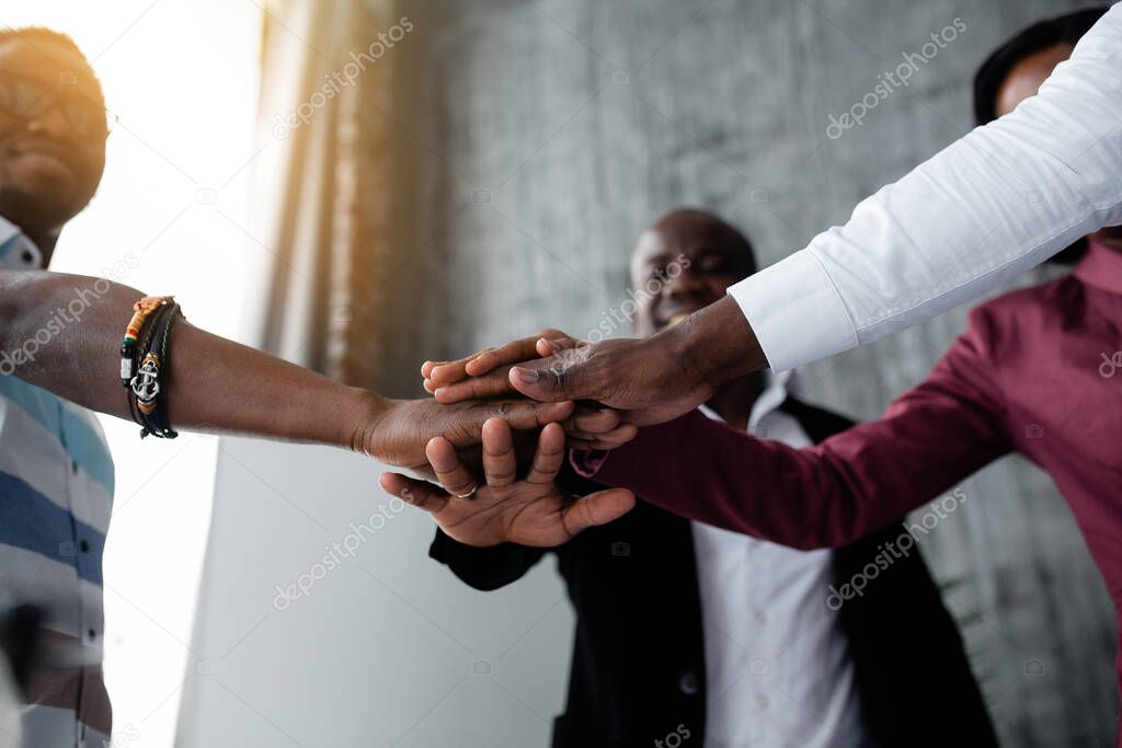 Bottom view of black colleagues who joined hands for hard team work against racism among countries of the world.