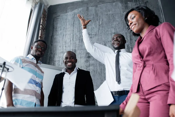 Visão inferior de colegas negros que jogam papel e sorriem em honra de completar uma ordem para um grande projeto — Fotografia de Stock