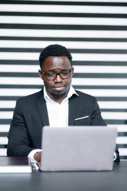 Afrikalı ofis çalışanı bir dizüstü bilgisayarda yeni bir uygulama geliştiriyor. Profesyonel bir programcının iş akışı.