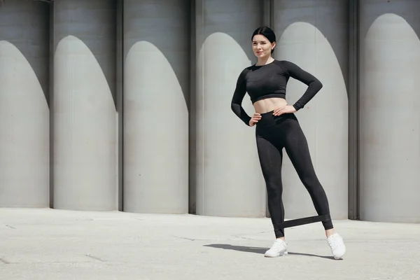 Fullständigt porträtt av en Pilatestränare som gör övningar med ett sportgummiband på vristerna för att stärka benmusklerna i sidled. — Stockfoto
