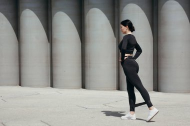 Antrenör profili pilates yapıyor. Siyah spor bant genişleticisi ile sokak ortasında.