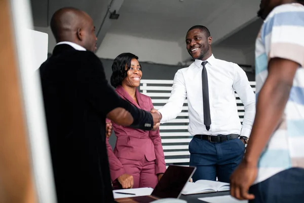 Черный бизнесмен пожимает руку своему новому партнеру, афроамериканцу в белой рубашке и улыбается. Заключить сделку . — стоковое фото