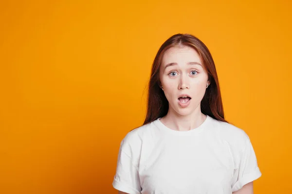 Fille aux cheveux rouges dans la surprise regarde à la caméra avec la bouche ouverte. Portrait photo de la fille est embarrassé et surpris. — Photo