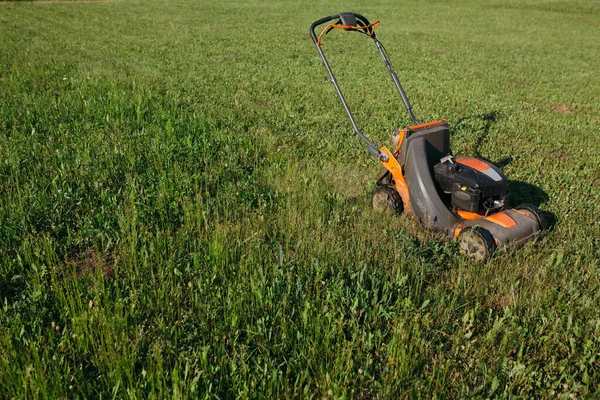 Photo du processus de coupe de la pelouse dans la banlieue avec la tondeuse. Entretien gazon longue pelouse. — Photo