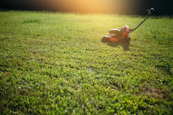 Zdjęcie kosiarki stojącej na świeżo ściętym trawniku w naturze w promieniach słońca — Zdjęcie stockowe