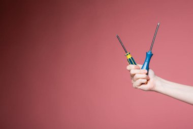 Pembe arka plandaki kadın eli iki tornavida tutuyor. İnşaat mağazaları için reklam pankartı.