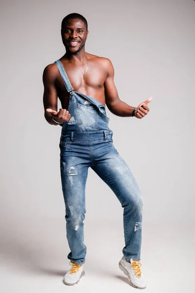 Μαύρος Αφρο-Αμερικανός με γυμνό κορμό σε τζιν παντελόνι με τιράντες σταυρώνει τα χέρια του στο στήθος.. — Φωτογραφία Αρχείου