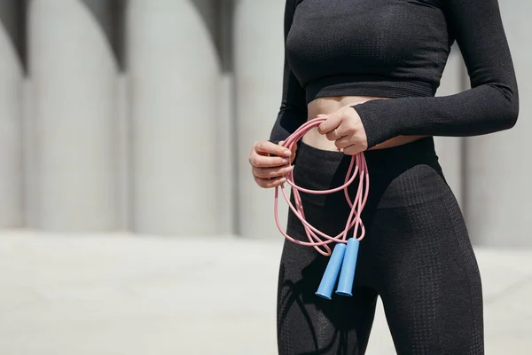 一名身穿紧身运动服的女孩手握绳索，准备在一个新鲜空气中的公园接受训练的特写镜头. — 图库照片