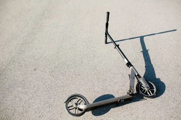 Foto de un scooter para viajar por la calle arrojado al asfalto en un día soleado . — Foto de Stock