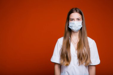 Uzun saçlı ve kırmızı arka planda beyaz önlüklü bir doktor kız portresi.
