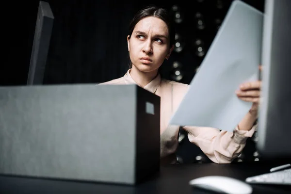 Obchodní dívka drží dokumenty v rukou, aby je dala do černé skříňky, zatímco sedí u stolu s vážnou tváří. — Stock fotografie