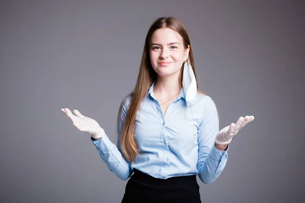 Woman business lady stands with arms apart and smiles at the end of quarantine on a gray background