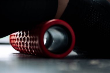 Sırtın bel kaslarının bağlarını güçlendirmek için spor masaj silindiri uzanan bir kadının yakın çekimi..