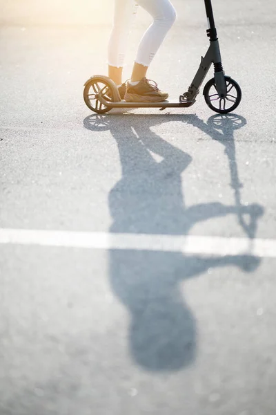 Una foto vertical de la sombra proyectada por el scooter y la chica que lo monta. Foto de un scooter para redes sociales —  Fotos de Stock