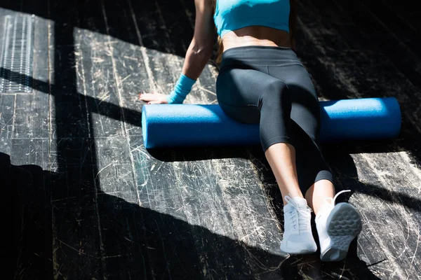 İnce, genç bir kadının gövdesi ve bacakları güneşin parlak ışınlarında spor yapmaya gider. Gluteal kasların bağlarını köpüklü rulo ile çözüyorum.