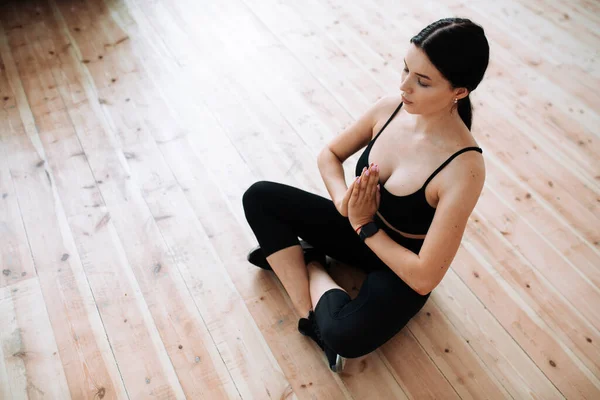Vedere de sus de meditație yoga antrenor în îmbrăcăminte sport negru ținându-se de mâini în fața lui și stând pe podea de lemn în poziție de lotus — Fotografie, imagine de stoc