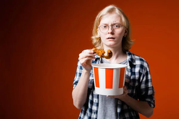 Tatmin olmamış genç sarışın bir kadın elinde fast food 'dan kızarmış tavuk budu tutuyor ve diyeti hatırlıyor.. — Stok fotoğraf