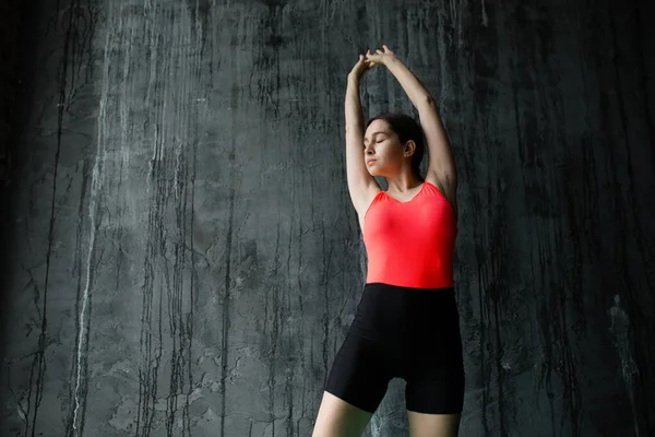 Seorang wanita muda olahraga Asia berlatih yoga terhadap dinding abu-abu dan melakukan latihan untuk meregangkan otot punggung. — Stok Foto