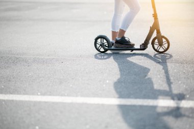 Scooter süren birinin fotoğrafı ve dışarıdaki asfalta düşen uzun bir gölge. Spor malzemeleri kavramı