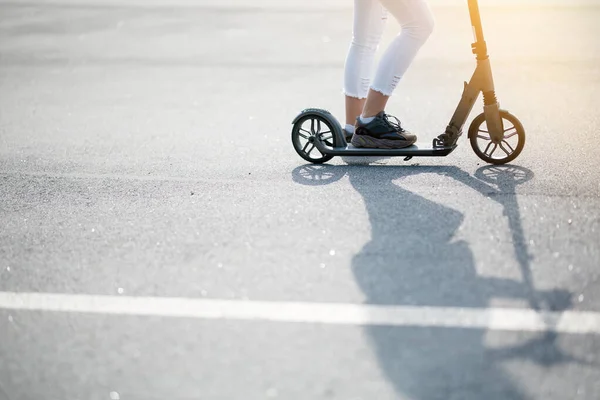 Foto de una persona montando un scooter y una larga sombra cayendo sobre el asfalto exterior. Concepto de artículos deportivos —  Fotos de Stock