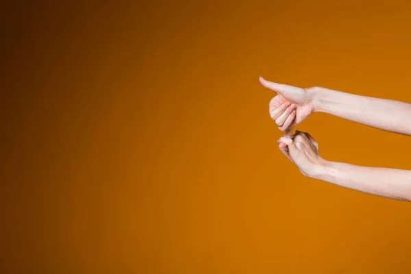 Delgadas manos femeninas sobre un gesto de fondo naranja como un signo de aprobación. — Foto de Stock