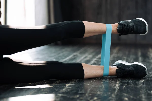 Close-up of a female leg with a sports elastic band for training. Girl fitness trainer doing exercises for legs