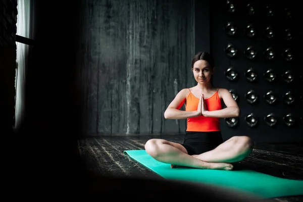 Portretul unei fete meditatoare antrenor de yoga în poziție de lotus care și-a pliat mâinile într-un gest de rugăciune în fața pieptului ei așezat pe o podea de lemn — Fotografie, imagine de stoc