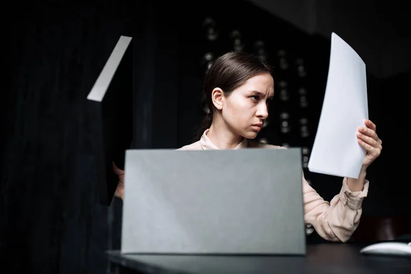 Un trabajador confuso no es capaz de encontrar una solución. Mujer sentada en la oficina Escritorio con una computadora y una carpeta para documentos — Foto de Stock